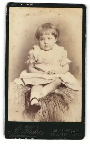 Fotografie A. Winter, Preston, kleines Kind auf Fell sitzend