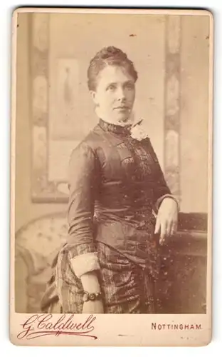 Fotografie G. Caldwell, Nottingham, Frau im Kleid stehend mit hohem Kragen und Blume daran