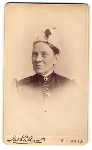 Fotografie E. Tham, Huddersfield, Dame mit Brosche am Kragen und Haube auf dem Kopf