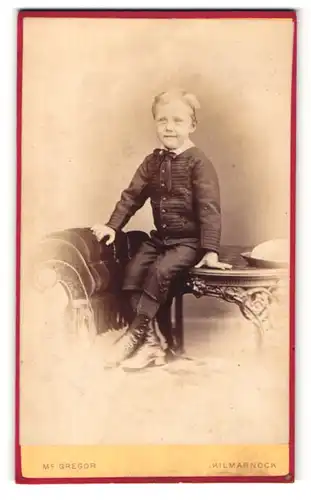 Fotografie Mc Gregor, Kilmarnock, Junge im Anzug mit Schleife am Hals auf Tisch sitzend