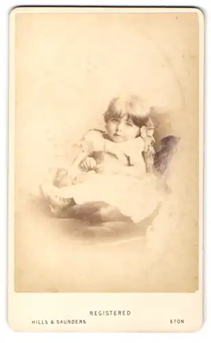 Fotografie Hills & Saunders, Eton, Portrait Kleinkind im Kleidchen auf einem Sessel