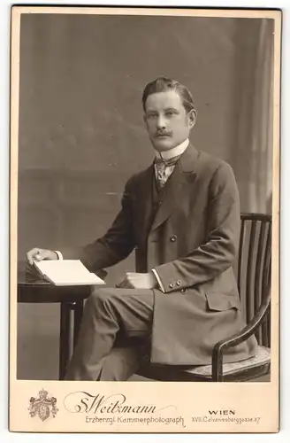 Fotografie S. Weitzmann, Wien, Portrait elegant gekleideter Herr mit Buch am Tisch sitzend