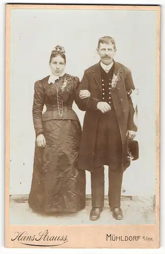 Fotografie Hans Strauss, Mühldorf a / Inn, Portrait bürgerliches Paar in festlicher Kleidung mit Ansteckblumen und Hut
