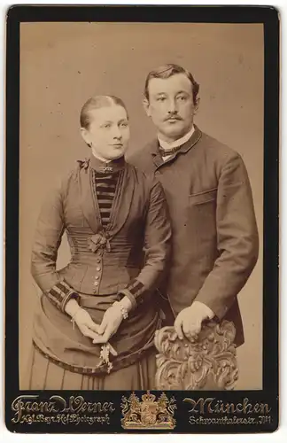 Fotografie Franz Werner, München, Portrait modisch gekleidetes Paar mit Blumen an Stuhl gelehnt