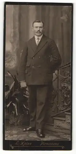 Fotografie L. Heine, Pirmasens, Portrait elegant gekleideter Herr mit Schnauzbart an Geländer gelehnt