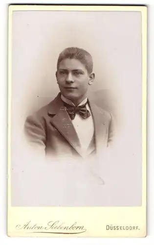 Fotografie Anton Siebenborn, Düsseldorf, Portrait hübscher junger Mann in Fliege und Jackett