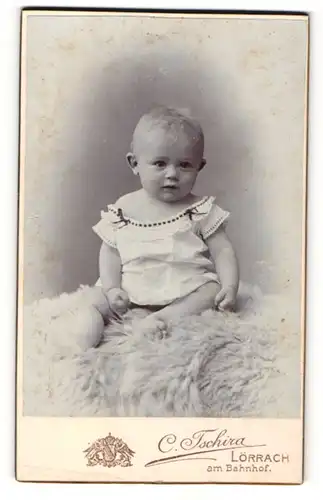 Fotografie C. Tschira, Lörrach, Portrait zuckersüsses Kleinkind auf Fell sitzend