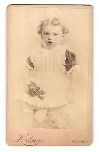 Fotografie Hodson, Retford, Portrait niedliches Kleinkind im hübschen Kleid auf Fell sitzend