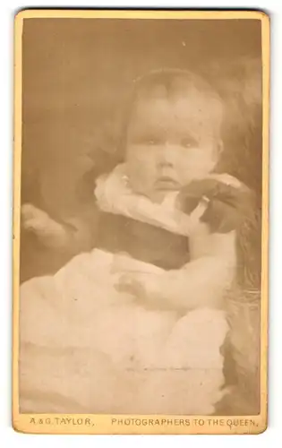 Fotografie A. & G. Taylor, Leeds, Portrait niedliches Baby im weissen Kleid mit Schleifchen