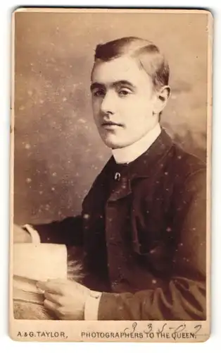 Fotografie A. & G. Taylor, London, Portrait elegant gekleideter Herr mit Buch an Fell gelehnt