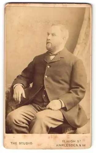 Fotografie The Harlesden Studio, Harlesden, Mann im Anzug mit Bart sitzend
