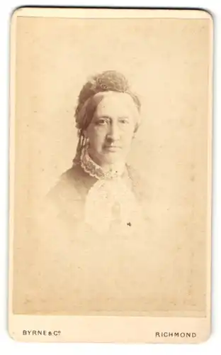 Fotografie Byrne & Co, Richmond, Portrait betagte Dame mit freundlichem Blick und Schleife am Kragen