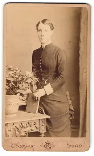 Fotografie C. Keeping, Exeter, Portrait elegant gekleidete Dame mit Buch an Tisch gelehnt