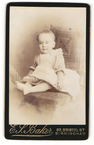 Fotografie E. S. Baker, Birmingham, Portrait sitzendes Kleinkind im hübschen Kleid mit kurzen Haaren
