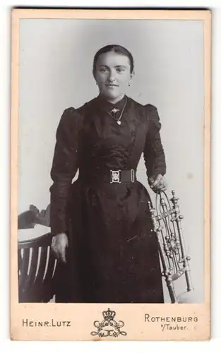 Fotografie Heinrich Lutz, Rothenburg o/Tauber , Junge Frau mit dunklen Haaren hält sich an verzierter Rückenlehne fest