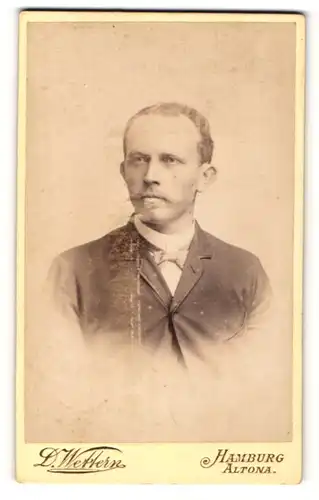 Fotografie D. Wettern, Hamburg, Herr mit kurzen Haaren und zugeknöpfter Jacke trägt eine Fliege
