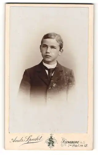 Fotografie Andr. Specht, Flensburg, Junge mit hellen Augen trägt eine dunkle Jacke und schwarze Krawatte