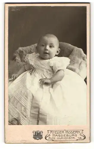 Fotografie Hugo Paulsen, Magdeburg, Portrait sitzendes Baby im weissen Kleid mit Schleifchen