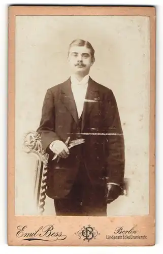 Fotografie Emil Bess, Berlin, Portrait junger Herr im Anzug mit Schnurrbart und Handschuhen