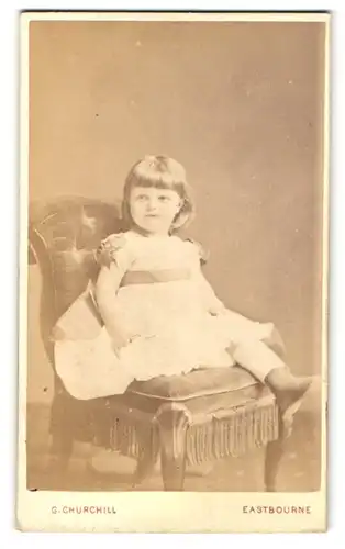 Fotografie G. Churchill, Eastbourne, Portrait niedliches Mädchen im weissen Kleidchen mit Schleifen