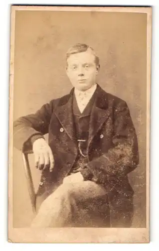 Fotografie W. Sherwood, Workington, Mann mit Seitenscheitel sitzend und überschlagenen Beinen