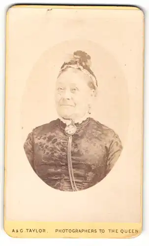 Fotografie A & G Taylor, London, ältere Dame mit Hochsteckfrisur, im dunklen Kleid