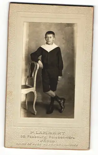 Fotografie P. Lambert, Paris, Junge in Knickerbockern lehnt an Stuhl