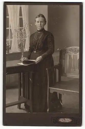 Fotografie Emil Hoppe, Hartmannsdorf, Portrait elegant gekleidete Dame mit Zeitung an Tisch gelehnt
