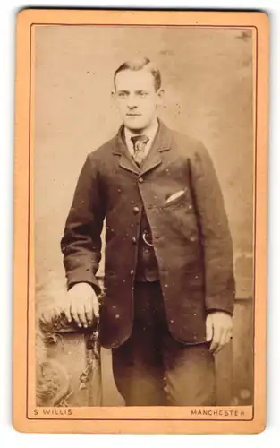 Fotografie S. Willis, Manchester, Portrait bürgerlicher Herr im Anzug mit Fell an Sockel gelehnt
