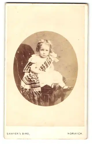 Fotografie Sawyer & Bird, Norwich, Portrait sitzendes Mädchen im hübschen Kleid mit Schärpe