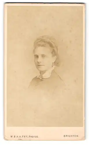 Fotografie W. & A. H. Fry, Brighton, Portrait junge Dame mit Hochsteckfrisur und Kragenbrosche