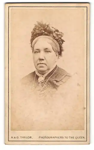 Fotografie A. & G. Taylor, Newcastle, Frau trägt Haube mit aufwendiger Verzierung aus Pflanzen und Halskette