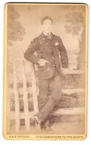 Fotografie A. & G. Taylor, Newcastle, Mann in dunklem anzug lehnt mit der Hand in der Tasche an Holzzaun