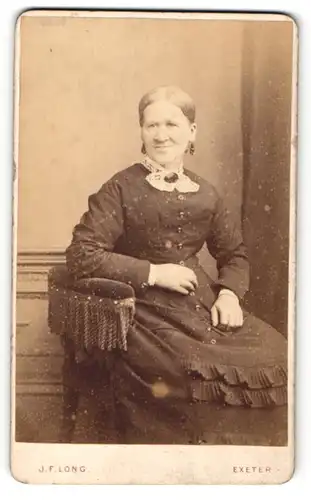 Fotografie J. F. Long, Exeter, Portrait sitzende Dame im eleganten Kleid mit Kragenbrosche