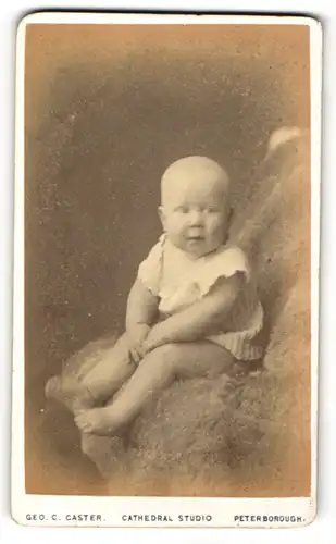 Fotografie Geo C. Caster, Peterborough, Portrait niedliches Baby auf einem Fell porträtiert