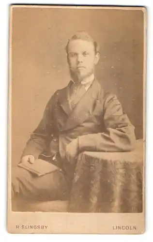 Fotografie R. Slingsby, Lincoln, Portrait bürgerlicher Herr mit Bart und Buch am Tisch sitzend
