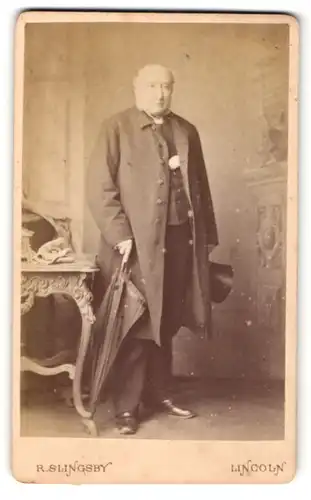 Fotografie R. Slingsby, Lincoln, Portrait älterer Herr im Mantel mit Schirm und Zylinder