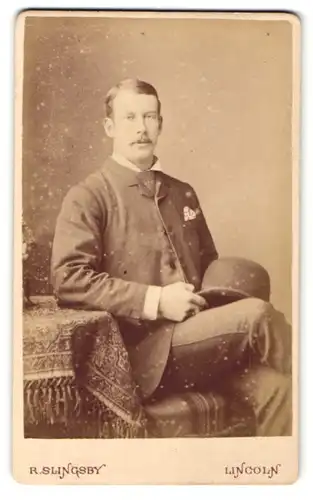 Fotografie R. Slingsby, Lincoln, Portrait bürgerlicher Herr mit Hut am Tisch sitzend