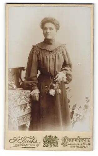 Fotografie J. Fuchs, Dresden, Portrait bürgerliche Dame mit Blumen an Tisch gelehnt