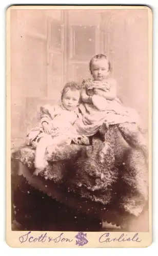 Fotografie Benjamin Scott, Carlisle, Portrait zwei zuckersüsse kleine Mädchen auf einem Fell sitzend
