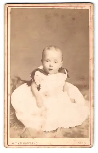 Fotografie W.T. & R. Gowland, York, Portrait Säugling in Kleidchen