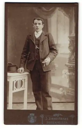 Fotografie J. Zimmermann, Eggenfelden, Portrait junger Herr im Anzug mit Zigarre an Tisch gelehnt