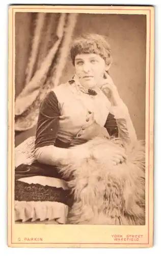 Fotografie G. Parkin, Wakefield, Portrait sitzende Dame im modischen Kleid auf Fell gestützt