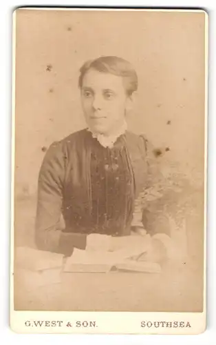 Fotografie G. West & Son, Southsea, Portrait bürgerliche Dame mit Buch am Tisch sitzend