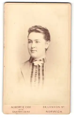 Fotografie Albert E. Coe, Norwich, Portrait Frau mit zurückgekömmten Haaren im Kleid mit weisser Fliege