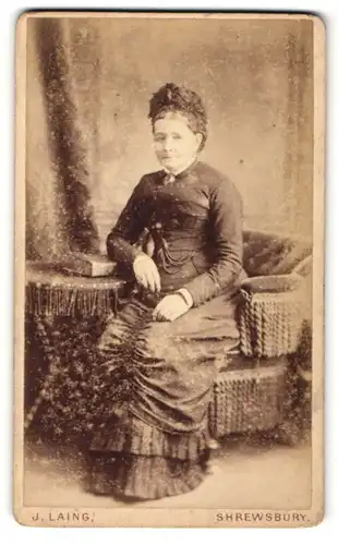 Fotografie J. Laing, Shrewsbury, Portrait ältere Dame im hübschen Kleid am Tisch sitzend