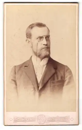 Fotografie C. Ruf, Freiburg, Mann mit bügelloser Brille und Vollbart trägt eine dunkle Jacke