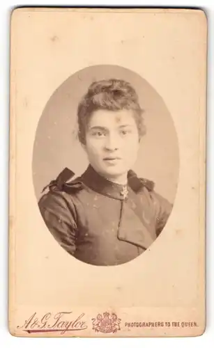 Fotografie A. & G. Taylor, Sheffield, Junge Frau mit Dutt im Kleid mit Schleifenapplikationen