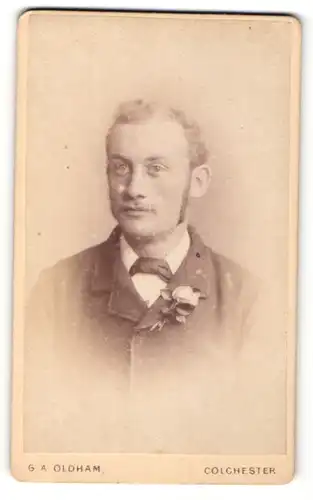 Fotografie G. A. Oldham, Colchester, Herr mit Backenbart im Anzug mit Ansteckblume