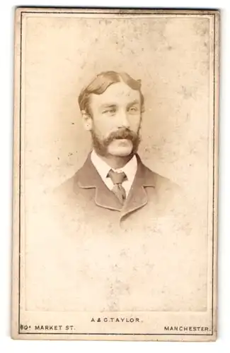 Fotografie A & G Taylor, Manchester, fröhlich zur Seite blickender junger Mann mit Mittelscheitel und Bart